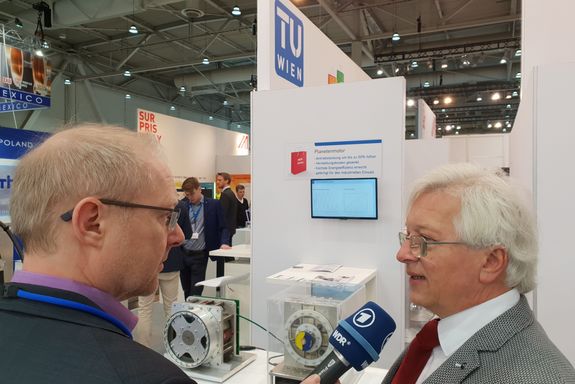 Prof. Dr. Schrödl in interview with an WDR-journalist infront of the planetary motor exponat at the TU Wien stand.