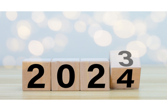 Vier Holzwürfel mit den Zahlen 2023. Der Würfel ganz rechts ist halb gekippt und zeigt neben der 3 auch die Zahl 4.