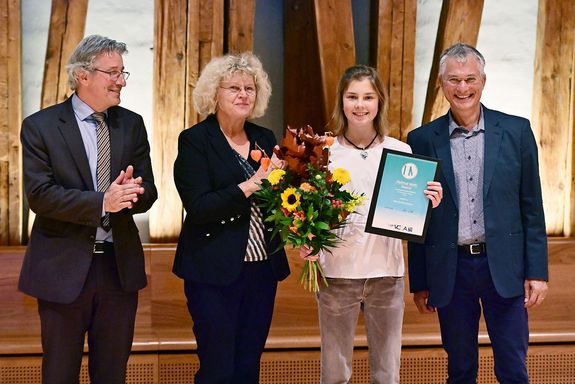 Ehrung mit Urkunde und Blumen auf der Bühne des Kuppelsaals.