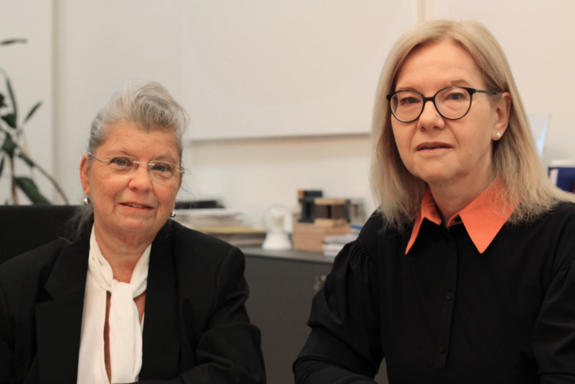 Betriebsrätin Marik links, mit schwarzem Jackett und weißer Bluse) und TUW-Vizerektorin Steiger rechts, mit schwarzem Pullover und Bluse mit orangenem Kragen, beide sitzend, Bürohintergrund.