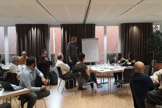 Group of people sitting in meeting room, one person at flipchart