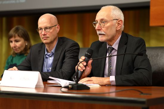 Drei Sprecher, eine Frau, zwei Männer, sitzen einem Tisch.