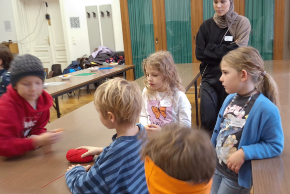 Kindergruppe sitzend bei Tisch und spielend