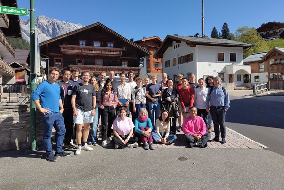 people standing an sitting in front of mountain hut