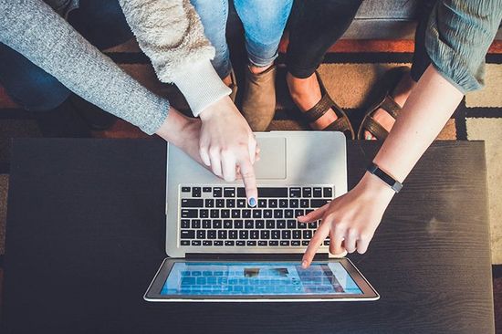 Studierende zeigen auf Laptop