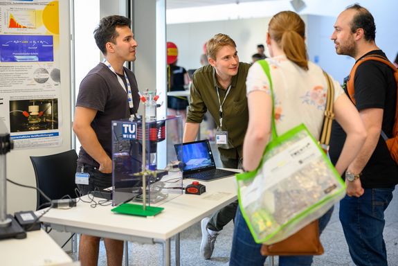 Zwei Wissenschaftler und zwei Besucher_innen betrachten Exponate und unterhalten sich.