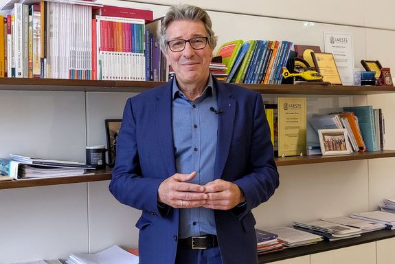 VR Kurt Matyas vor Bücherwand stehend in seinem Büro