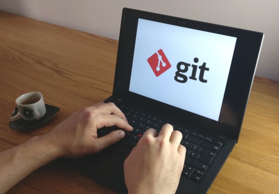 Hands typing on a laptop keyboard, on the screen the git icon.