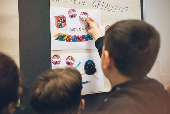 Kinder von hinten kleben Sricker auf ein Plakat.