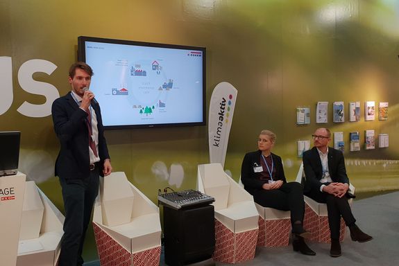 (from left to right) Moritz Bühner (Fritz Egger GmbH) presenting, standing. two more presenters sitting, watching him: Dr. Simone Spitzer (TU Wien), Prof. Dr. René Hofmann (TU Wien) - all in front of a big flat screen