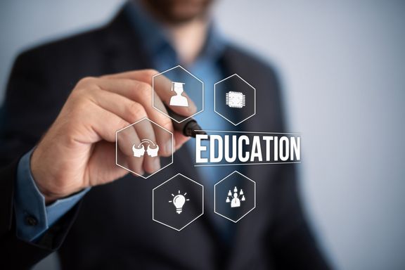 Person die auf eine Glastafel schreibt, mehrere Piktogramme zum Thema Bildung mit dem Wort "EDUCATION"