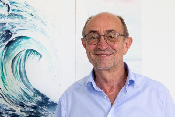 Portrait von Günter Blöschl, links im Bild eine Zeichnung einer Welle. 