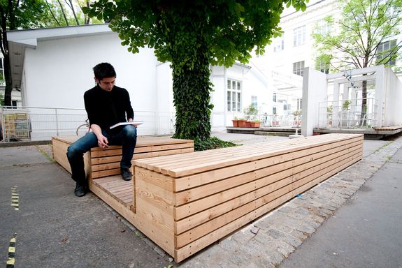 Wooden bench in the inner courtyard of the TU Vienna with one person on it