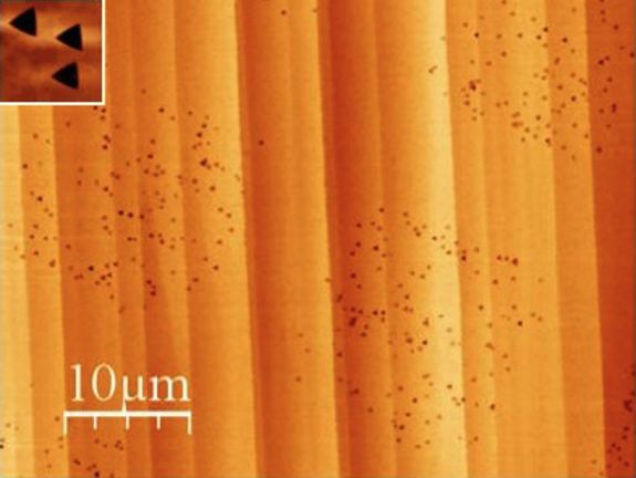 Kalziumfluorid-Oberfläche, beschossen mit Xenon-Ionen. Nach dem Ätzen werden dreieckige Löcher sichtbar (oben).