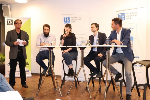 Eine weitere Aufnahme des Podiums und des Moderators. Diesmal spricht wieder Susanne Kaiser ins Mikrofon.