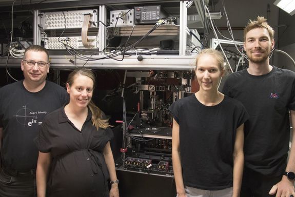 Four people in the lab, behind them measuring equipment and cables