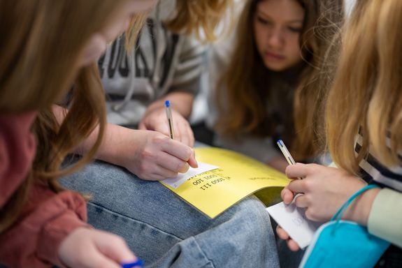 Kinder sitzend füllen gemeinsam Zettel aus