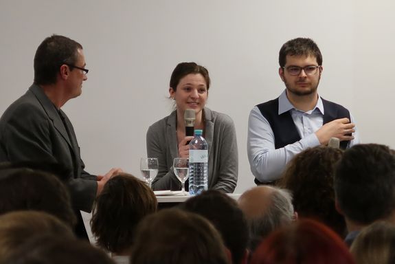 Großaufnahme vom Moderator, Elisabeth Gruber und Florian Libisch. Frau Gruber spricht gerade ins Mikrofon.