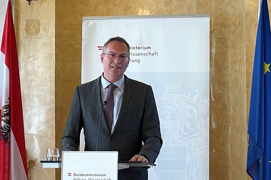 Peter Ertl vor Rednerpult, daneben die Flaggen von Österreich und der EU