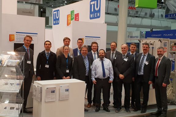 TU Wien team at the Hannover Messe 2019 - with Christian Kiene WKO-stand manager Advantage Austria (right) TU Wien Team (1 woman, 11 men) standing side by side in 2 rows, on the right Christian Kiene (Advantage Austria - WKO) in fornt of the TU stand at Hannover Messe 2019