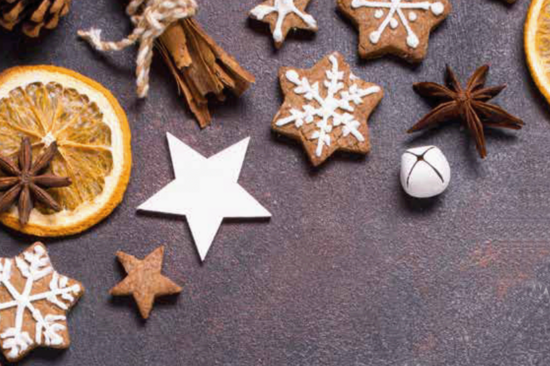 Weihnachtskekse und getrocknete Orangenscheiben auf graublauem Tuch.