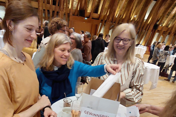 Drei Frauen, darunter Vizerektorin Steiger und die Leiterin der Personalentwicklung, Heidi Pichler. Heidi Pichler, mit blauem Oberteil, zieht gerade einen Teilnahmeschein.. 