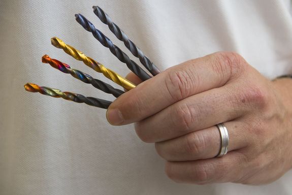 Prof. Mayrhofers hält 5 Bohrer verschiedener Farben in seiner linken Hand. Hand und Bohrer sind in Großaufnahmen zu sehen.