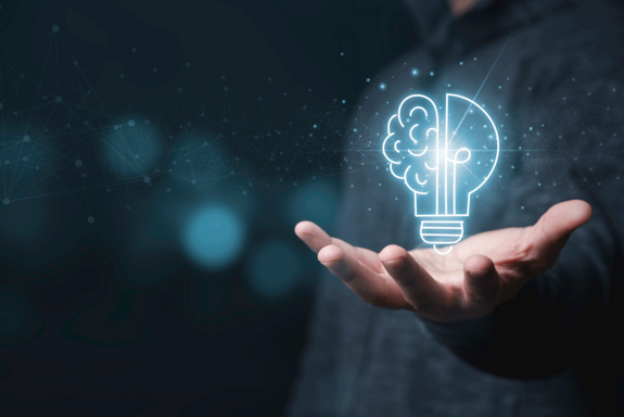 Geizeichnete und strahlende Glühbirne in einer Hand. Korper der haltenden Person nur schemenhaft im Hintergrund sichtbar, der in dunklem Blau gehalten ist.