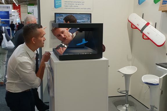 two men looking at the NGSolve hologram pyramid at the TU Wien stand