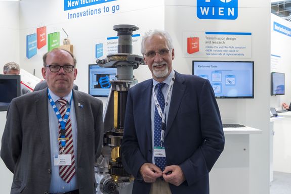 two men infront of a helicopter gearbox at the TU Wien stand