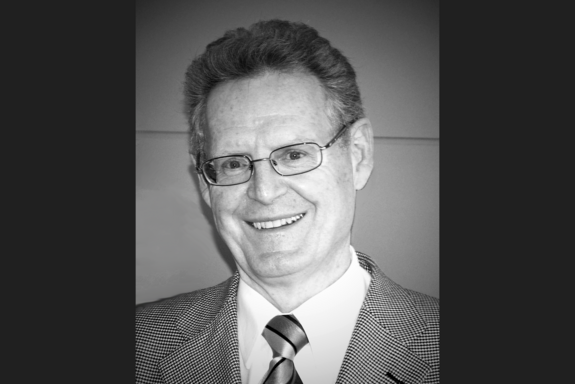 S/w Porträtbild von Prof. Grünbacher mit dunkelgrauen seitlichen Balken.