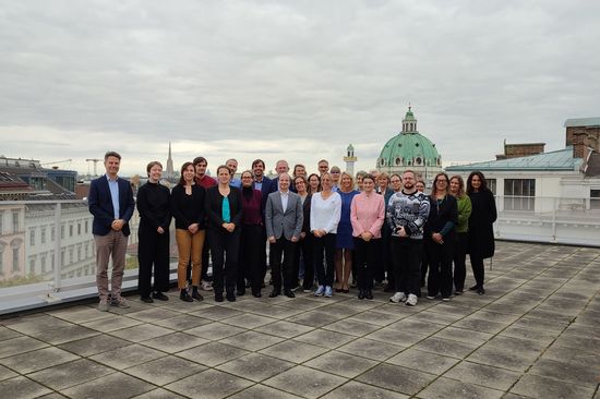 Gruppenfoto Menschen stehend auf Dachterrasse mit Blick über Wien im Hintergrund