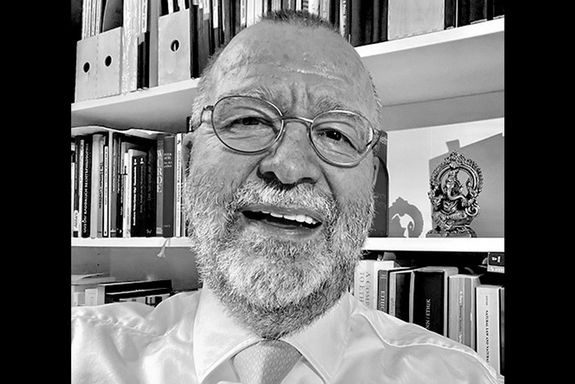 Schwarz-weiß Porträt eines älteren, lachenden Mannes mit gestutztem Vollbart. Dunkle Balken rechts und links