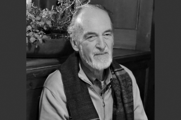 Schwarz-Weiß-Porträtbild mit links und rechts schwarzen Balken von Klaus Hoffmann. Der Oberkörper ist sichtbar. Er trägt einen hellen Pullover mit Zippverschluss und einen dunklen Schal.