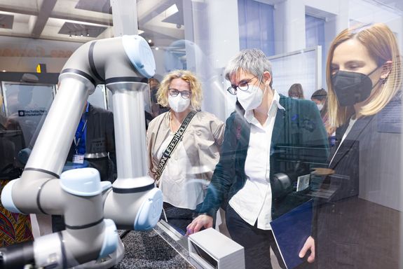 Drei Frauen beobachten einen Roboterarm