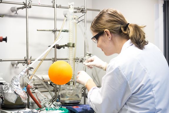 Frau in weißem Labormantel arbeitet an Maschine