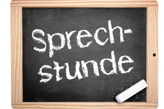 Tafel mit hellbraunem Rand und schwarzem Innenteil; Sprechstunde in Kreise darauf geschrieben, weiße Kreide rechts unten im Bild