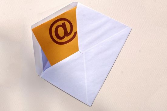 Forschungsnewsletter In einem weißen Kuvert liegt ein gelber Zettel mit einem schwarzen @-Symbol