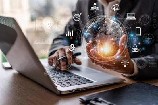 Ein Mensch sitzt an einem Laptop, davor schwirrt eine Wolke an Symbolen.