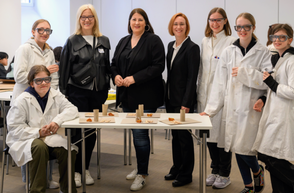 Gruppenfoto mit den Teilnehmerinnen im weißen Labormantel und den Politikerinnen sowie Vizerektorin Steiger. Die Damen tragen Schwarz.