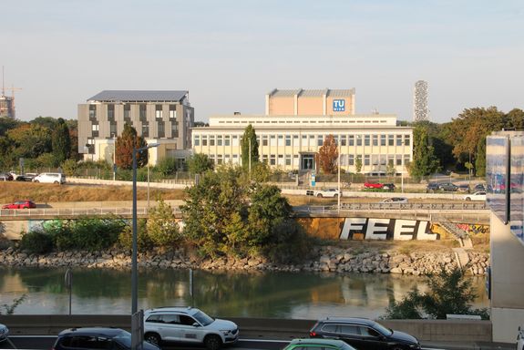 Sicht über den Donaukanal auf das Gelände des Atominstituts in der Abendsonne. Im Vordergrund Autos auf der Südautobahn stadtauswärts.