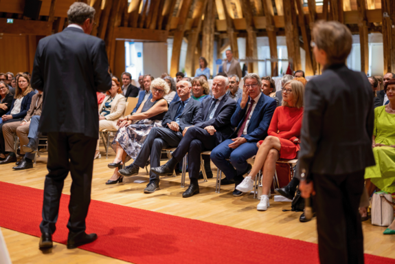 Rektorat in erster Reihe sitzend. Davor Person im Anzug, die spricht.