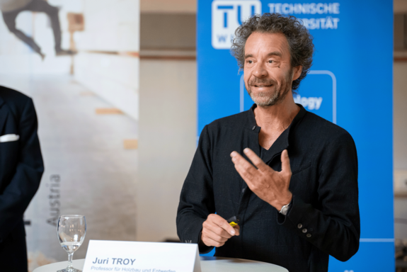 Juri Troy in schwarzer Jacke mit Stehkragen am Rednerpult.