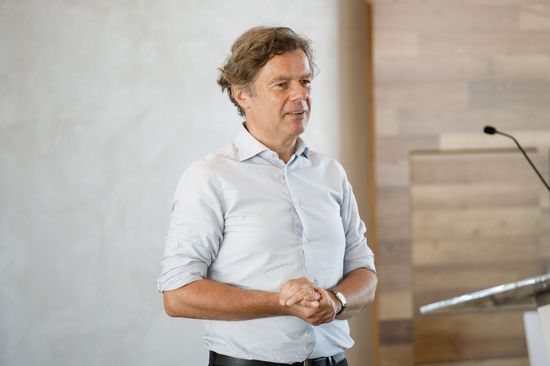 Wolfgang Güttel am Podium, Hintergrund Wand, rechts vorne Pult mit Mikrofon