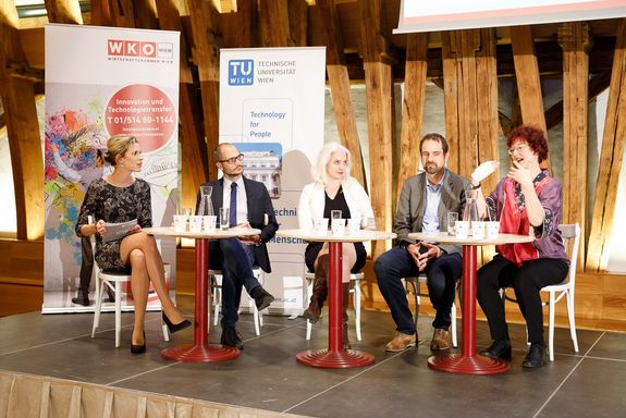 The presenter and the entire podium are seated on chairs on a raised platform. From left to right: Viktoria Raz, Florian Rudroff, Julie Rosser, Philipp Thurner and Ilse Gebeshuber.