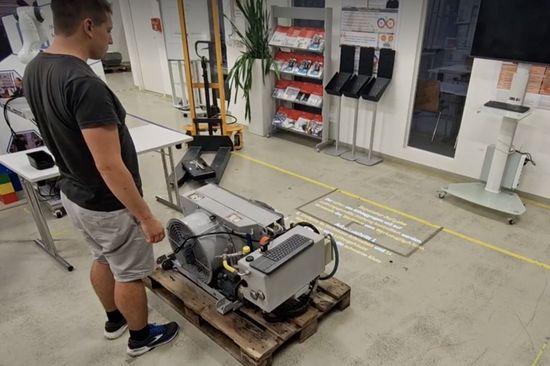 Mann in einer Fabrik vor einem Gerät, auf dem Boden projizierter Text