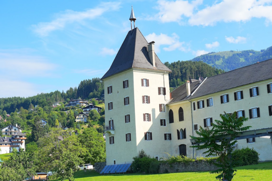 Kloster von einer Wiese aus gesehen. Im Hintergrund Berge.