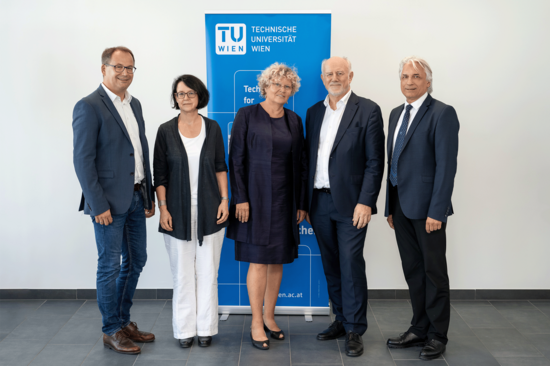 Gruppenbild mit blauer TU-Flagge im Hintergrund.