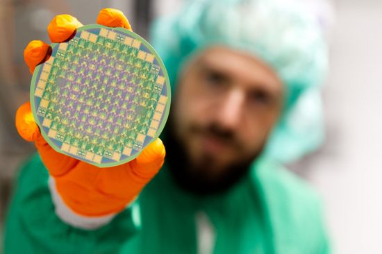 Ein Mann mit Schutzkleidung hält eine runde Platte in der Hand.