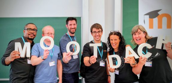 [Translate to English:] Menschen die Buchstaben halten die "Moot Dach" ergeben